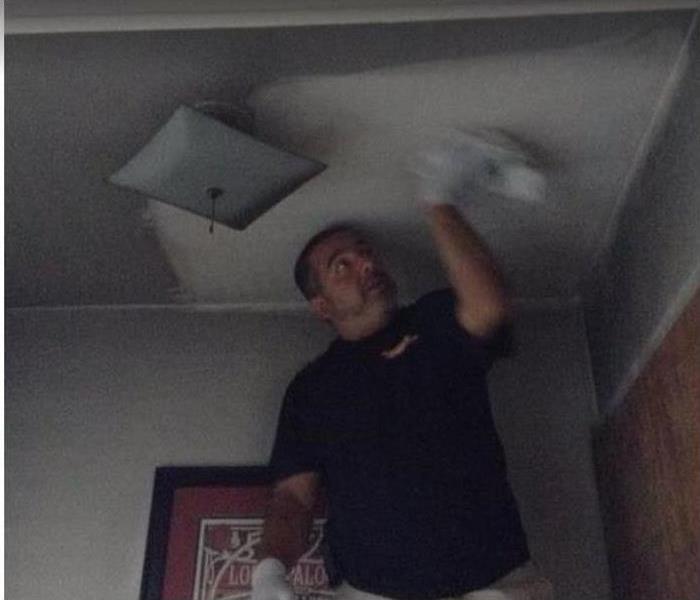 SERVPRO tech wiping soot from ceiling of fire damaged room