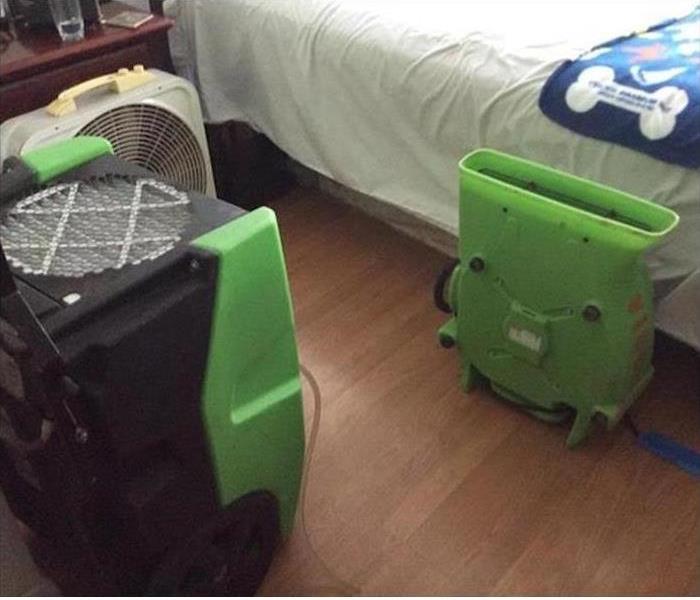 two of our drying equipment set up in a bedroom of house after the floors were hit with water damage